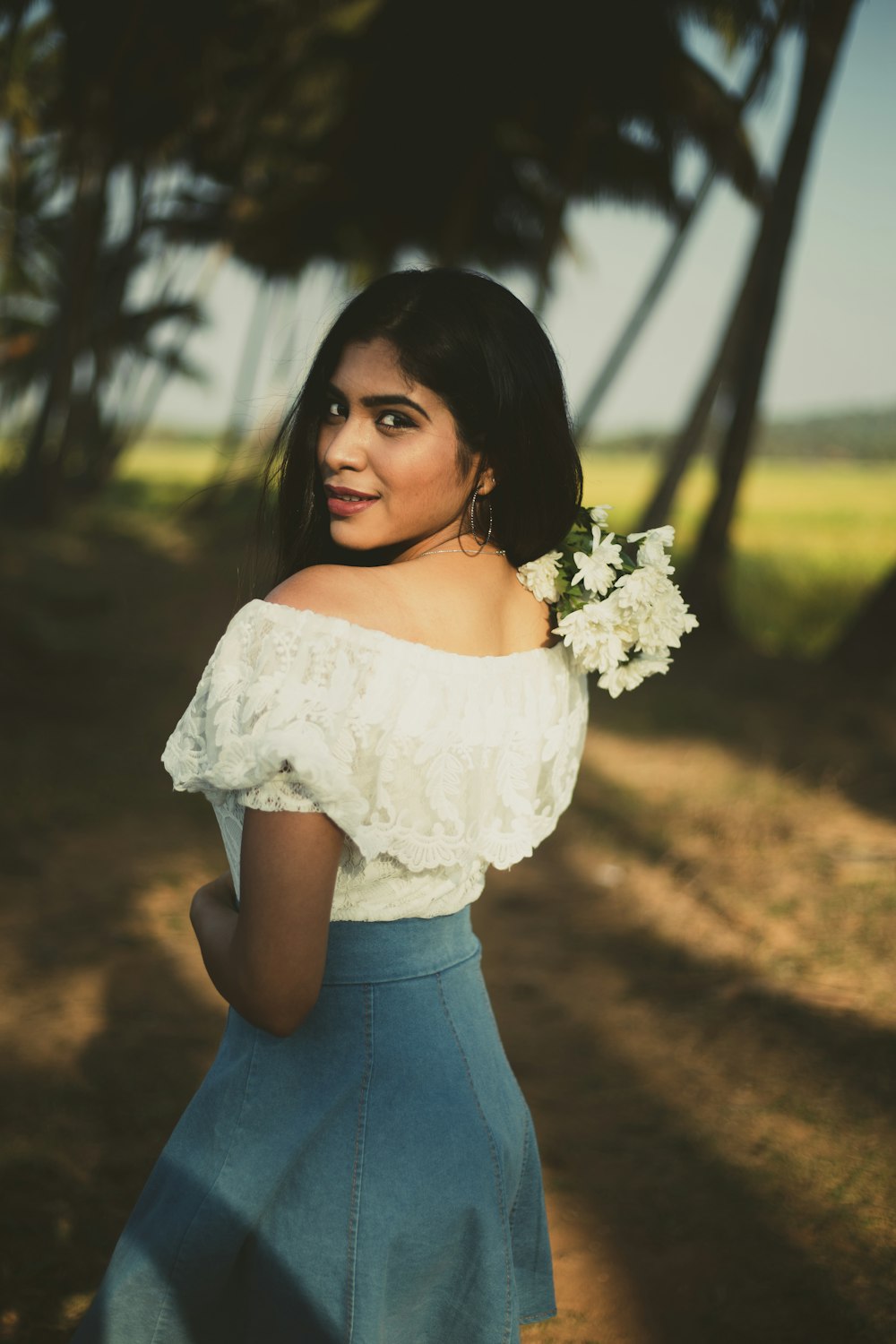 woman in white floral off shoulder top and blue denim skirt holding white flower bouquet