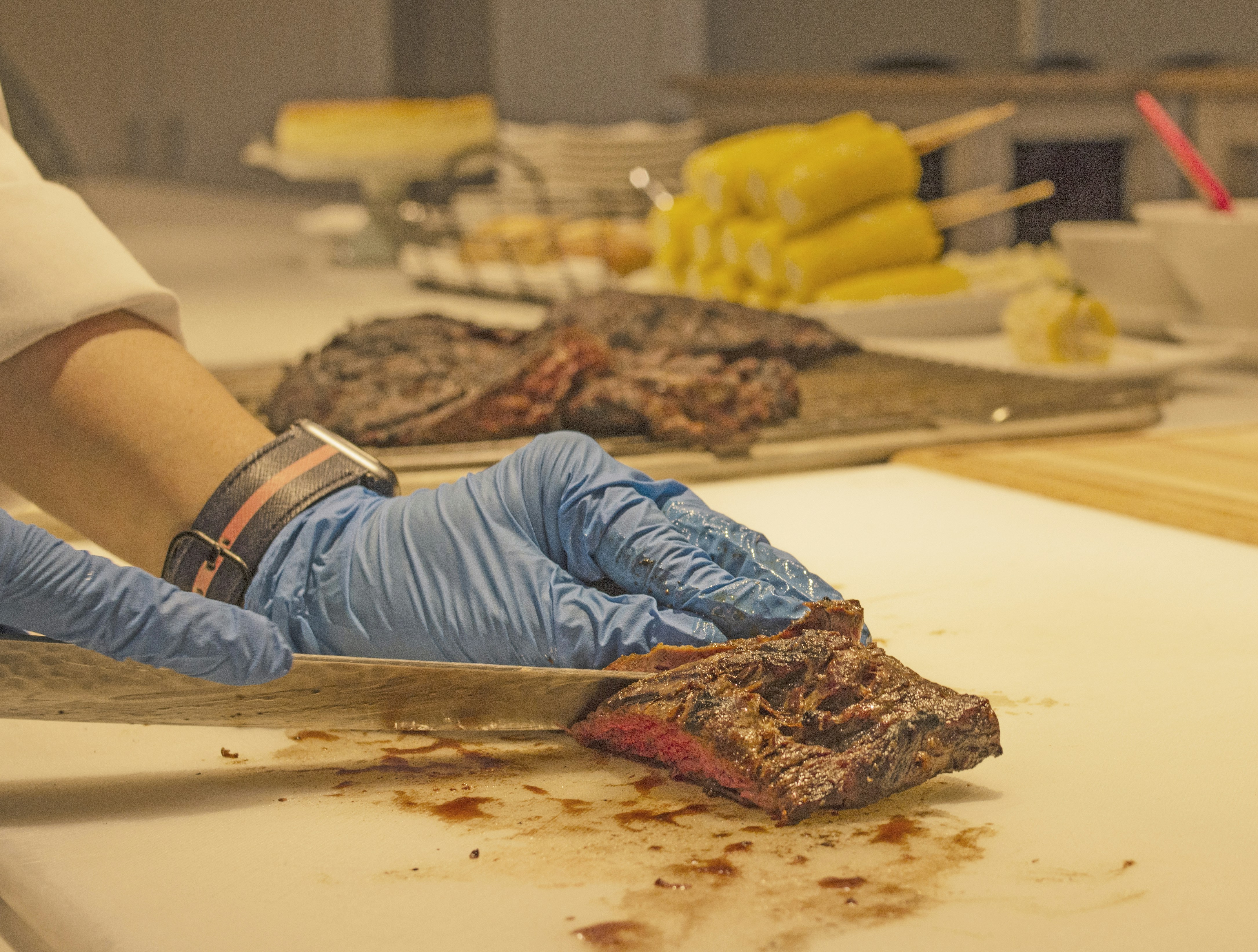 person in grey shirt slicing meat on white chopping board