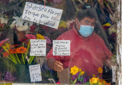 A friendly vendor using Mexican Sign Language to assist a customer with plants.