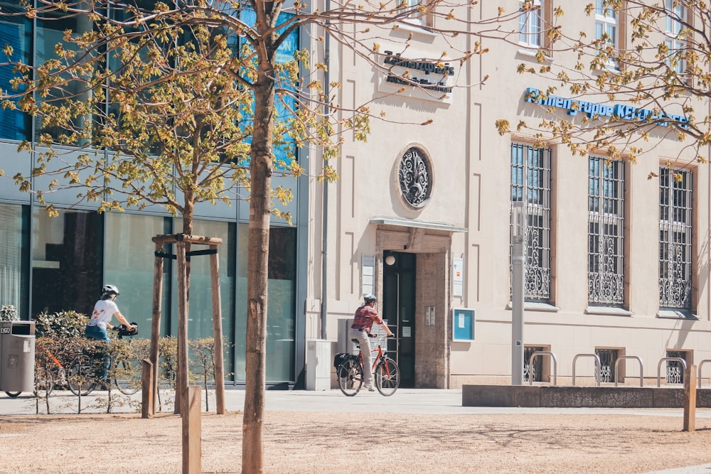 Hombre en chaqueta roja montando en bicicleta cerca del edificio durante el día