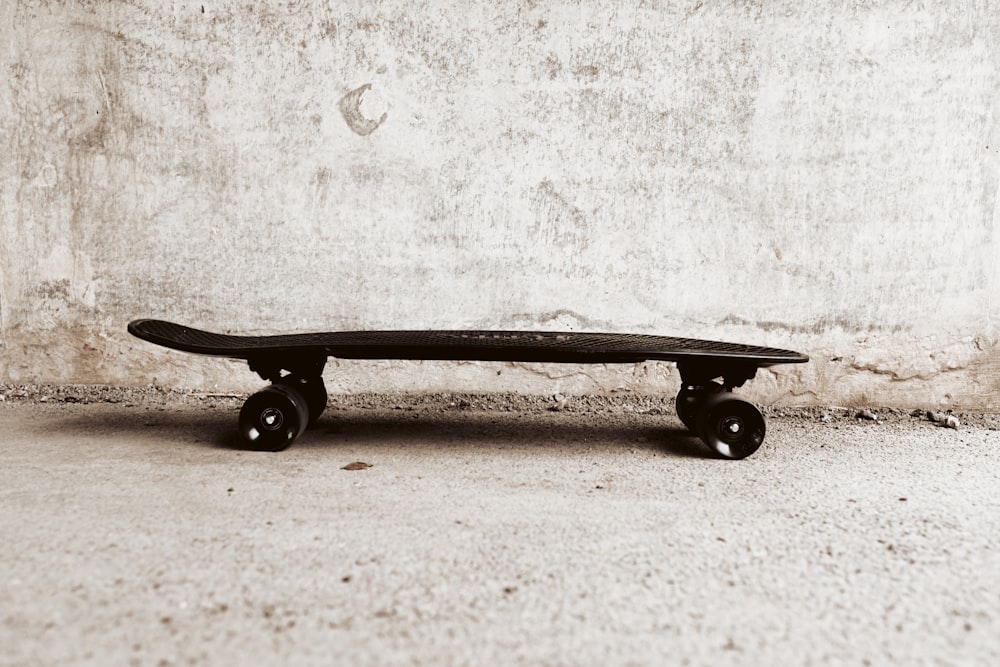 black skateboard leaning on white wall