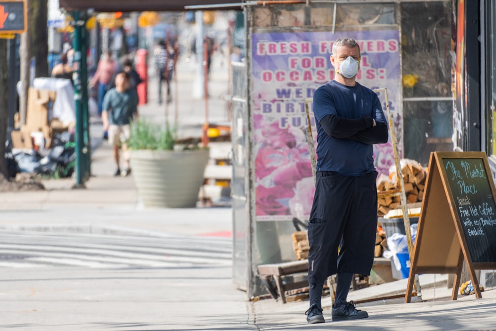 man in black suit standing on sidewalk during daytime