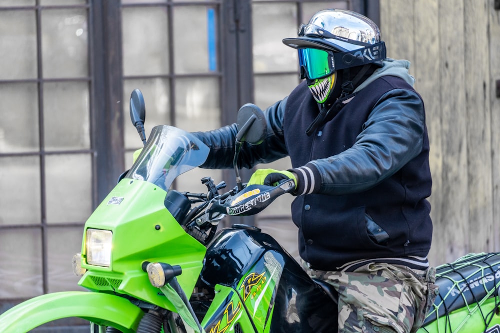 man in black jacket riding green and black sports bike