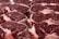 Several raw steak cuts of red meat with marbling are arranged in a neat, overlapping pattern. The meat appears fresh and ready for cooking.