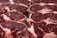Several raw steak cuts of red meat with marbling are arranged in a neat, overlapping pattern. The meat appears fresh and ready for cooking.
