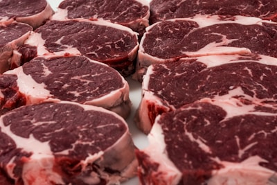 Close-up of fresh, marbled beef cuts arranged on a wooden board with herbs.