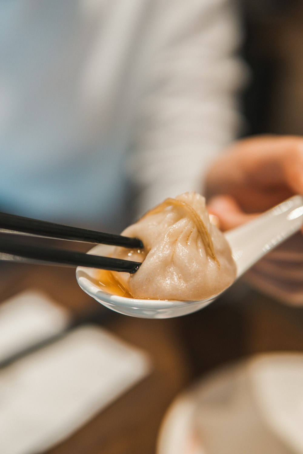 person holding white ceramic bowl with dim sum