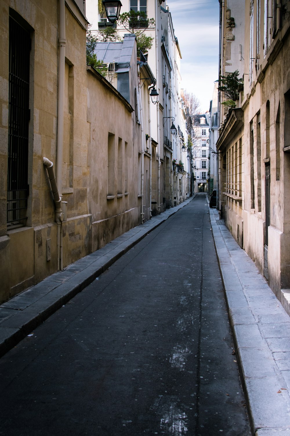 empty road between brown concrete buildings during daytime