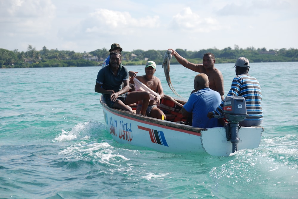 people riding on white and blue boat on sea during daytime