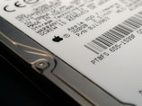 Close-up view of a hard drive with visible text and a barcode. The focus is on the details of the labeling, including technical specifications and a recognizable logo. The image captures the edge of the hard drive with a visible screw.