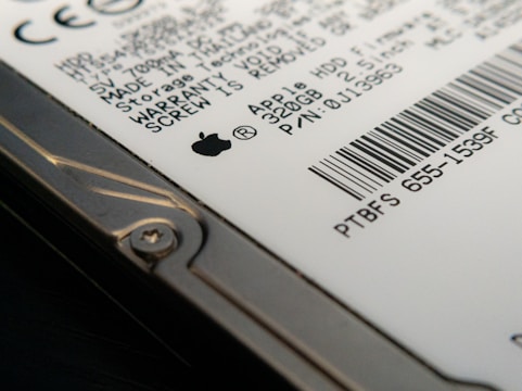 Close-up view of a hard drive with visible text and a barcode. The focus is on the details of the labeling, including technical specifications and a recognizable logo. The image captures the edge of the hard drive with a visible screw.