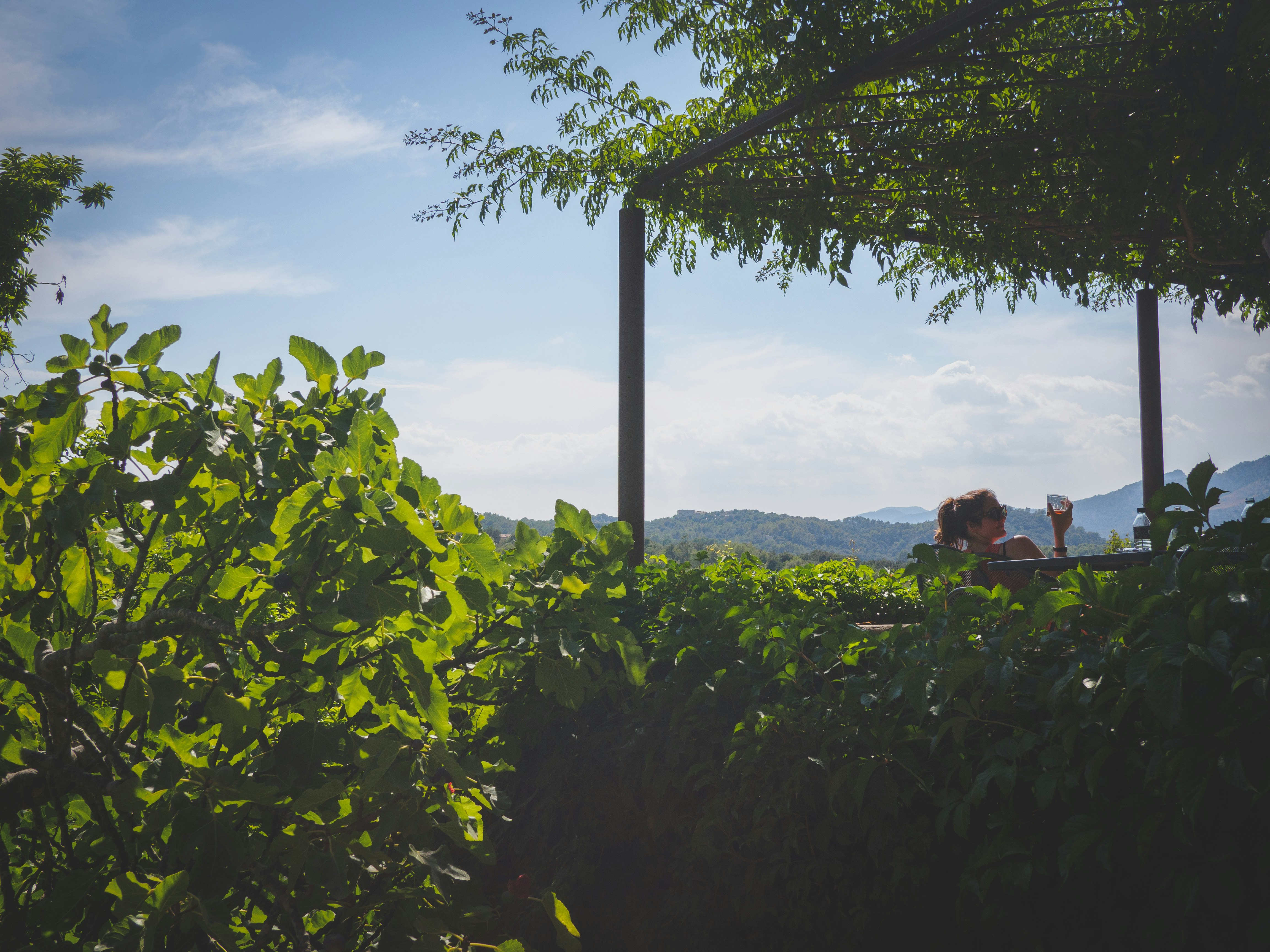 A woman enjoys a drink overlooking a mountain view