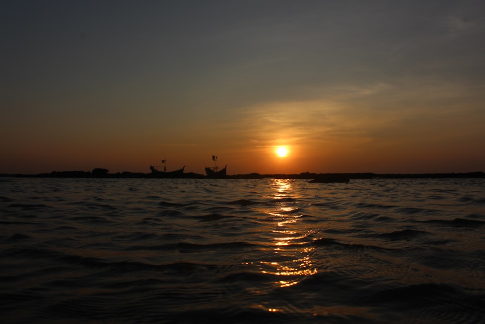 Silueta de la gente en el mar durante la puesta del sol