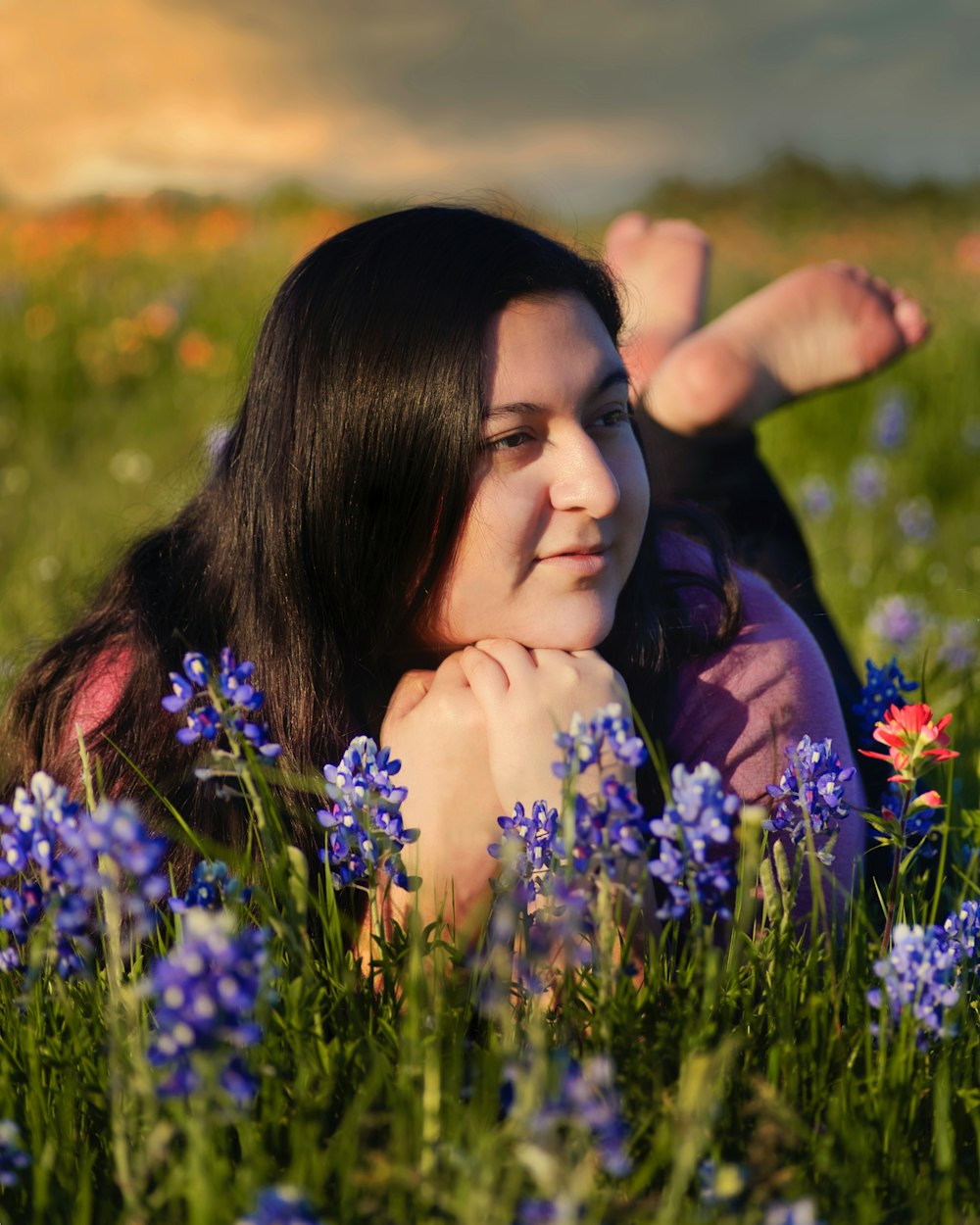 woman in purple shirt lying on green grass field during daytime