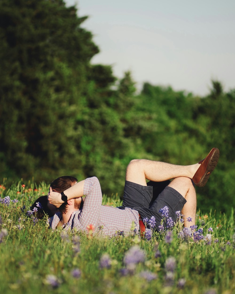 woman in black shirt and white shorts lying on grass field