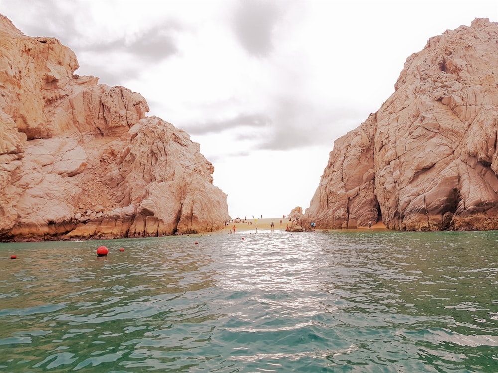 people in body of water between brown rocky mountains during daytime