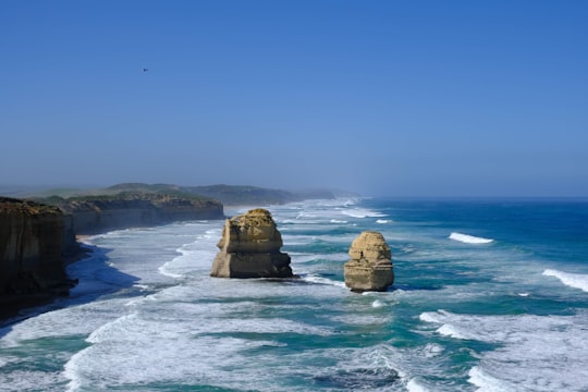 brown rock formation on blue sea under blue sky during daytime in Port Campbell National Park Australia