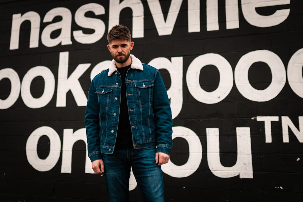 man in blue denim jacket standing beside black and white i love you print wall