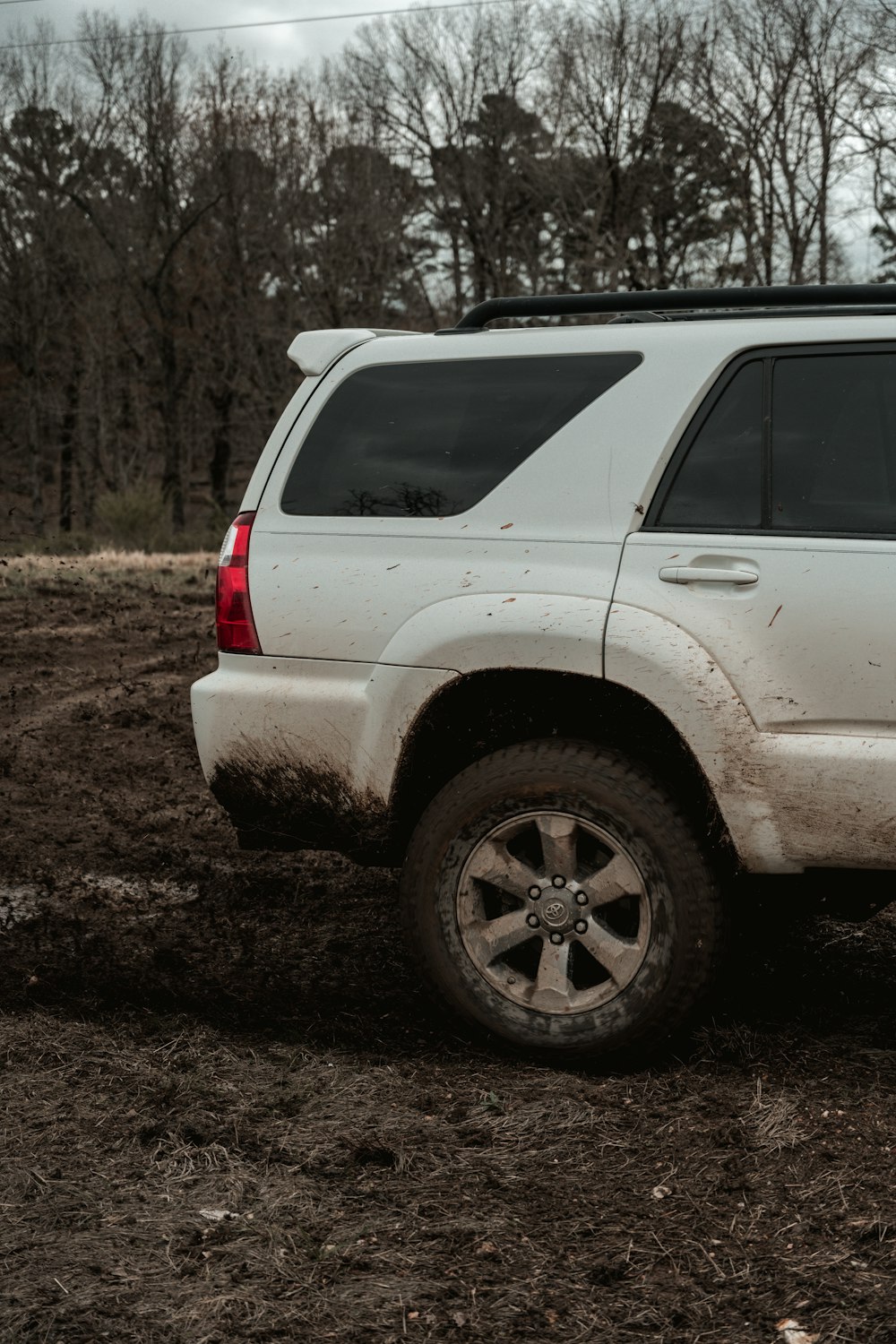 Before: white SUV heavily covered in mud along the lower body and wheels