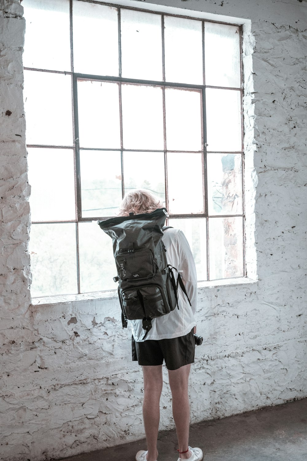 femme en veste grise et jupe noire debout devant la fenêtre pendant la journée