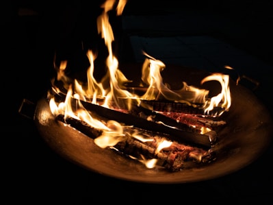 A stylish fire bowl glowing warmly in a cosy garden setting at dusk