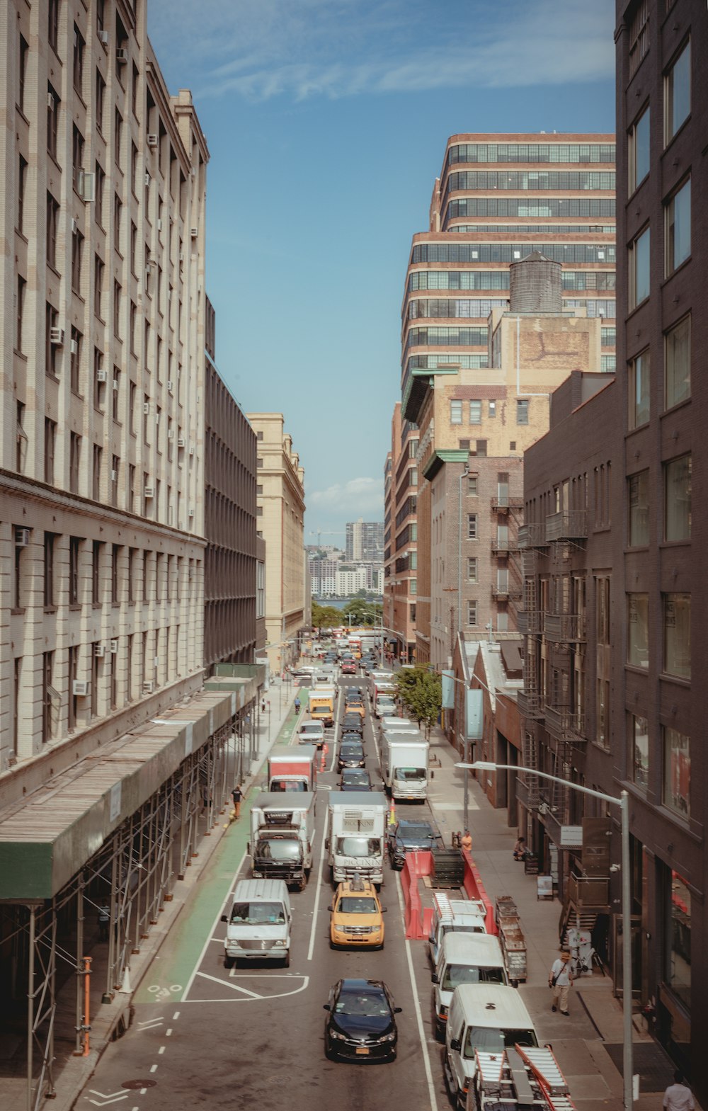 cars parked on street between high rise buildings during daytime