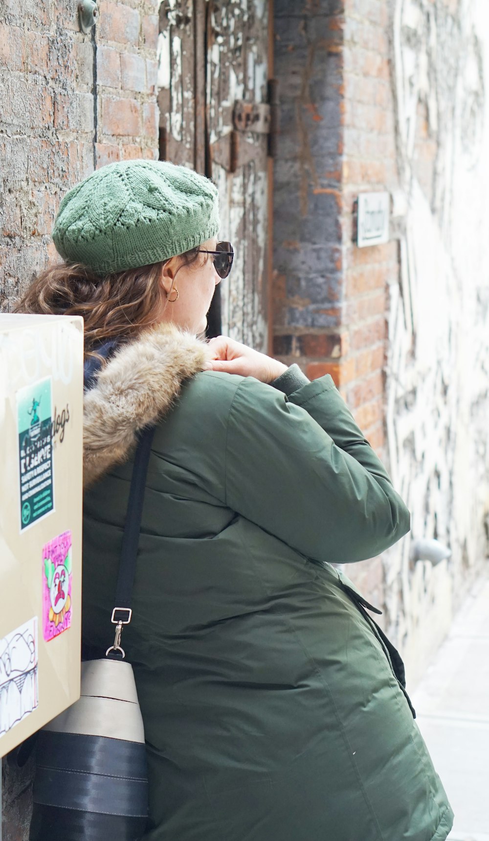 woman in green and brown parka jacket wearing green and black cap