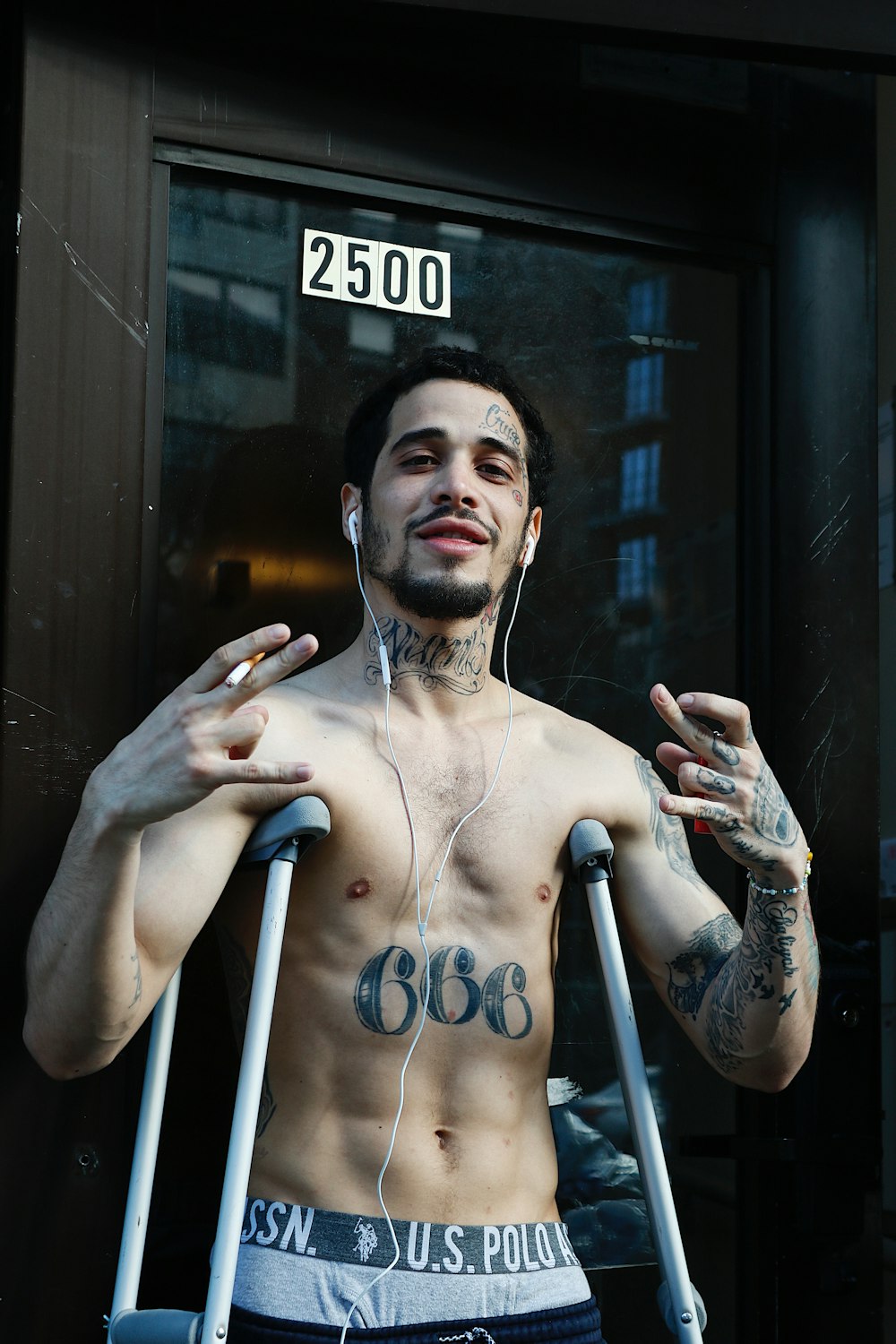 a shirtless man with earbuds standing in front of a door