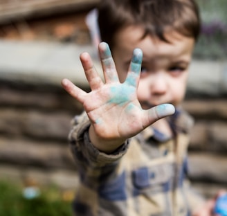 person in brown and black camouflage shirt with green paint on hand