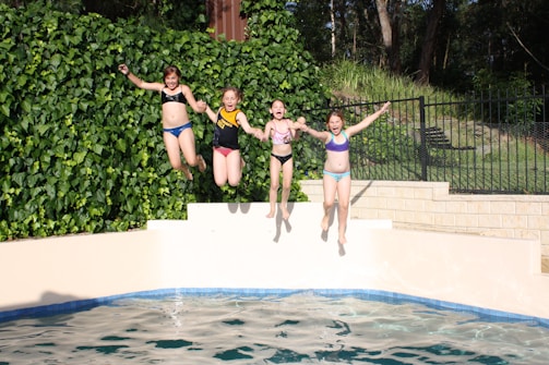 Smiling children jumping into the pool during swim class