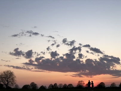 A cinematic shot of a wedding couple walking hand in hand along a scenic path at sunset.