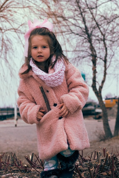 A young girl wearing a cozy winter coat and scarf outdoors.