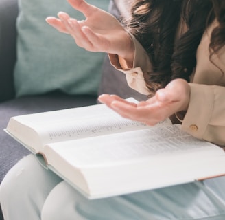 woman in beige long sleeve shirt holding white book