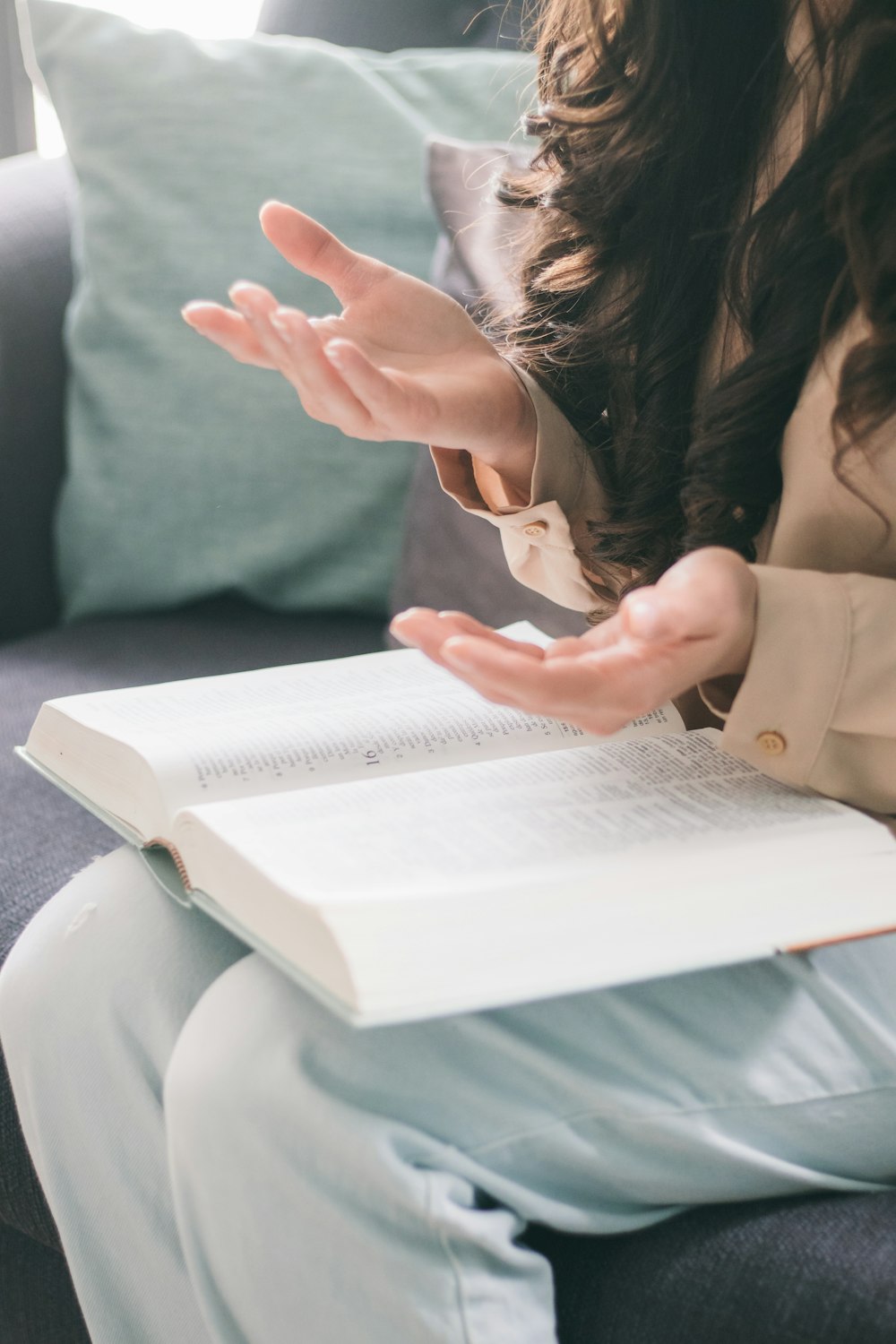 woman in beige long sleeve shirt holding white book