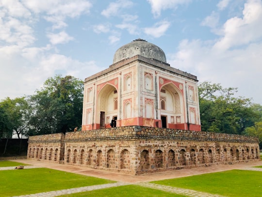 white concrete building near green grass field during daytime in Lakkar Wala Gumbad India