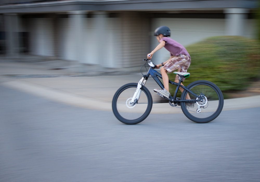 man in purple shirt riding bicycle on road during daytime