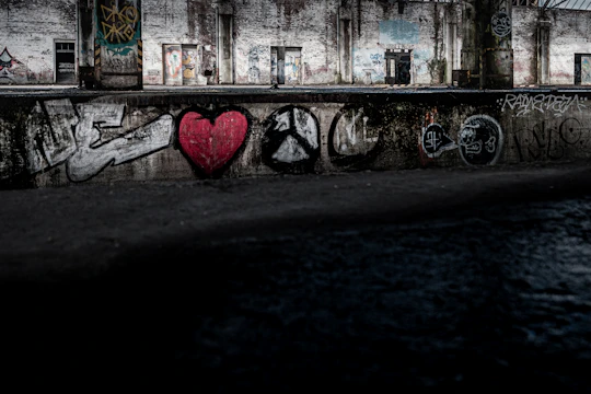 An abandoned, graffiti-covered building with broken windows reflecting a blood-red sunset.