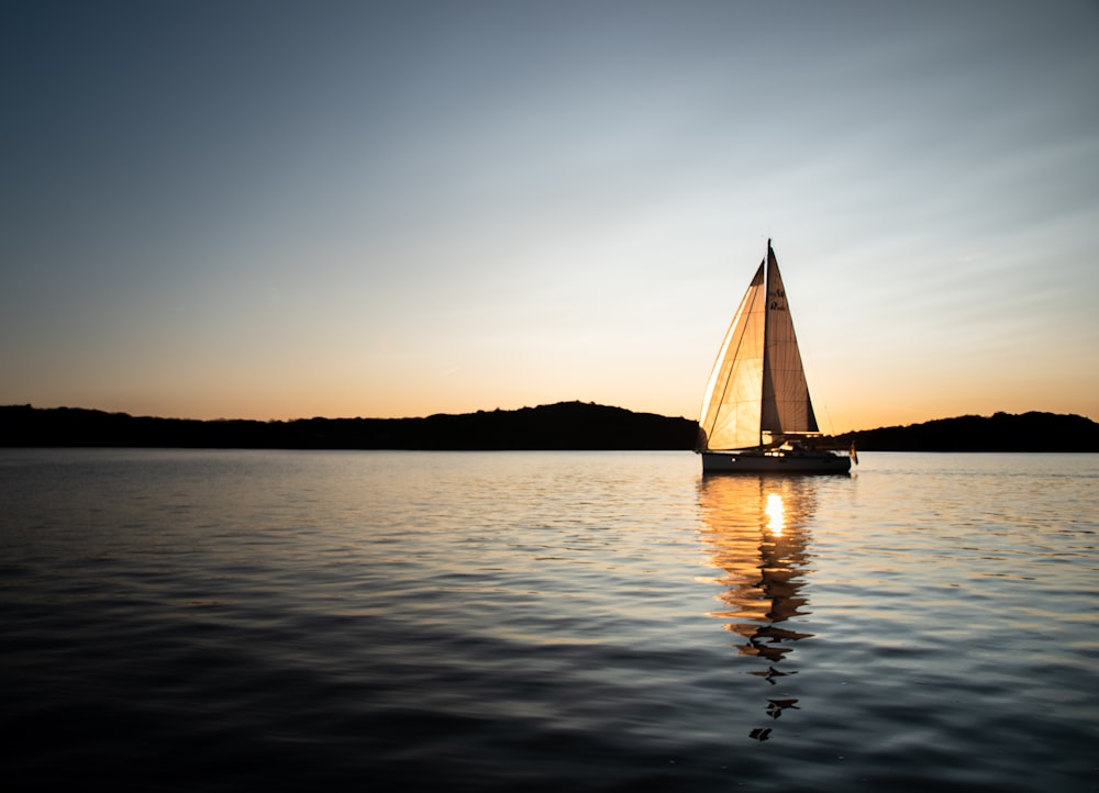 Velero blanco en el mar durante la puesta de sol