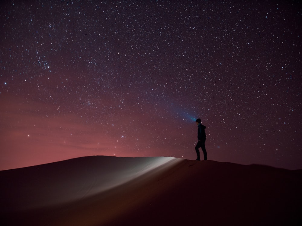 silhouette of person standing on sand during night time