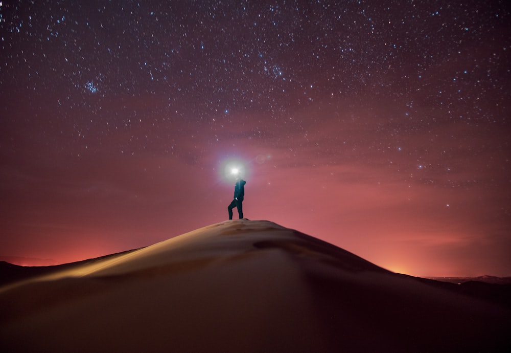 person standing on sand under starry night
