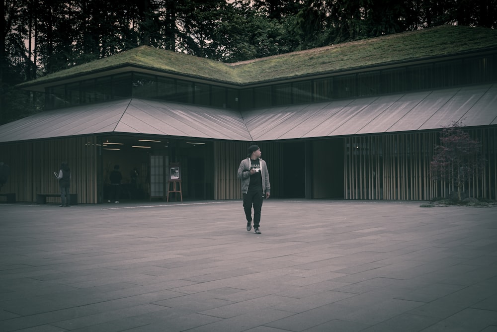 man in black jacket and black pants standing on gray concrete floor