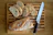 Wooden bread cutting board with crumb drawer on a rustic kitchen countertop.
