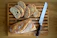 Wooden bread cutting board with crumb drawer on a rustic kitchen countertop.