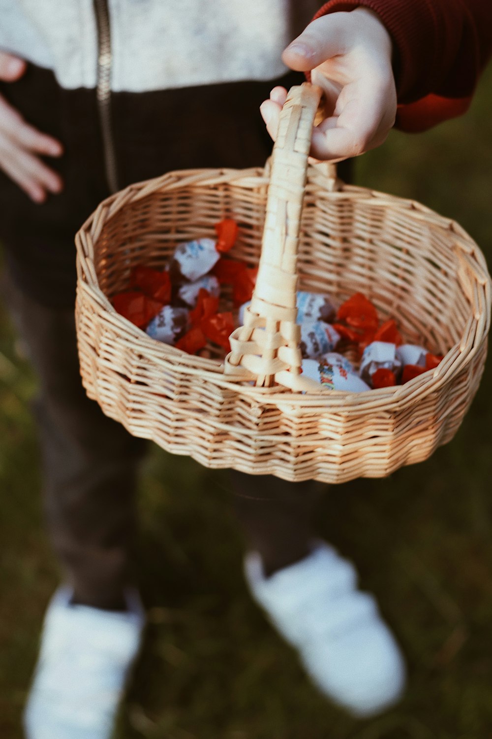 person holding brown woven basket with red and white fruits