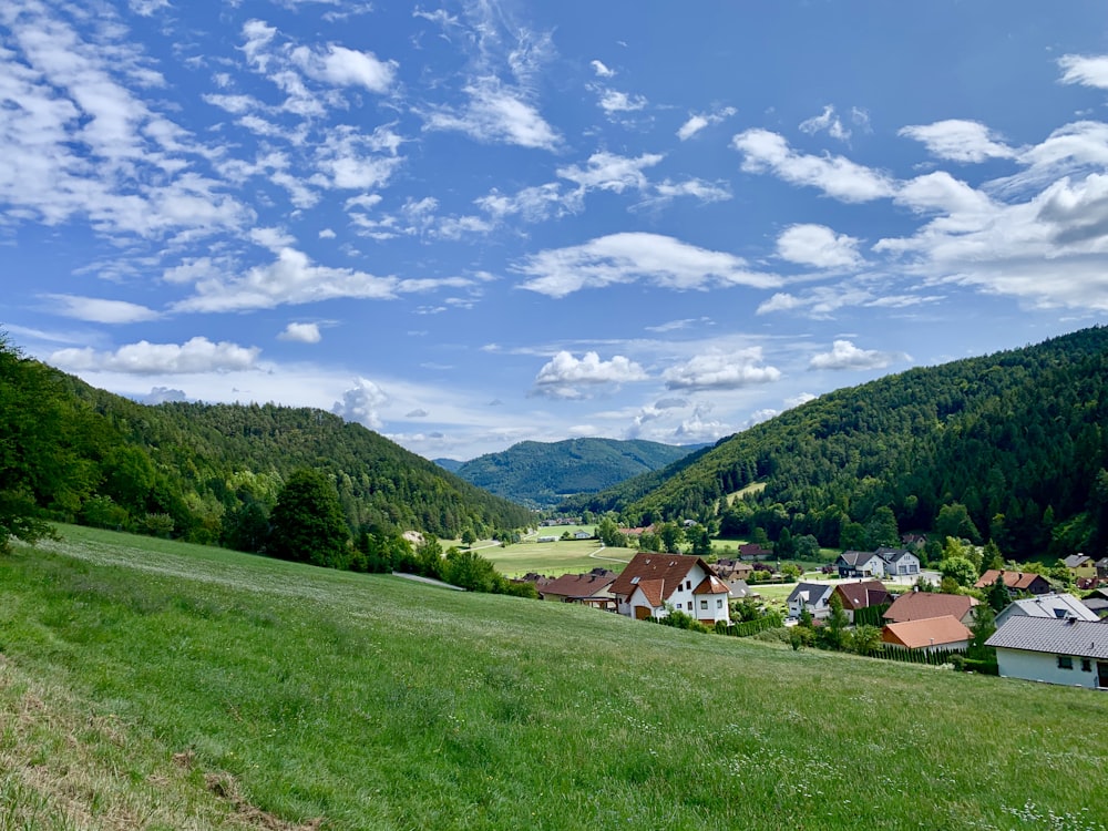 green grass field near houses under blue sky during daytime