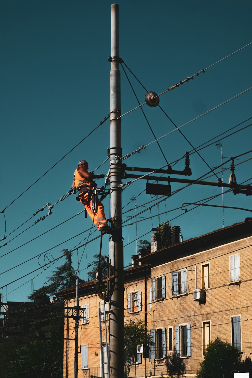 man in black t-shirt and brown pants standing on black metal post during daytime