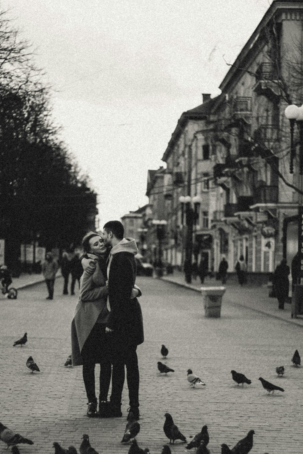 Photo en niveaux de gris d’une femme en manteau noir marchant dans la rue