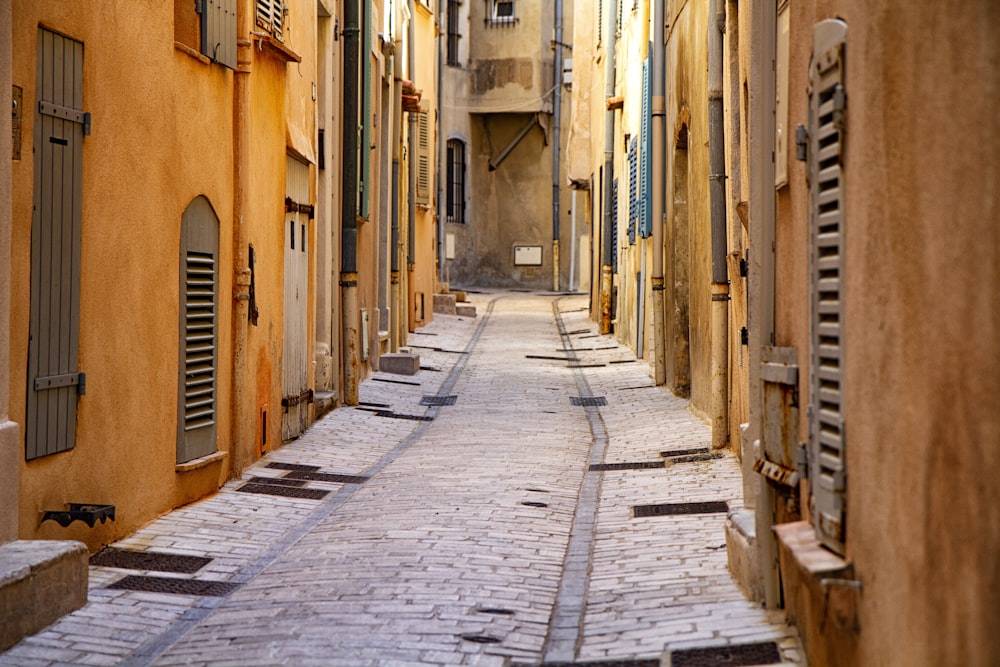 empty street between brown concrete buildings during daytime