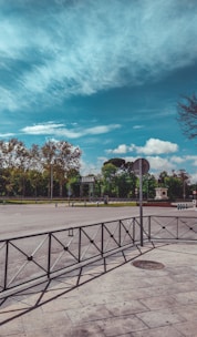 basketball court surrounded by trees under blue sky and white clouds during daytime