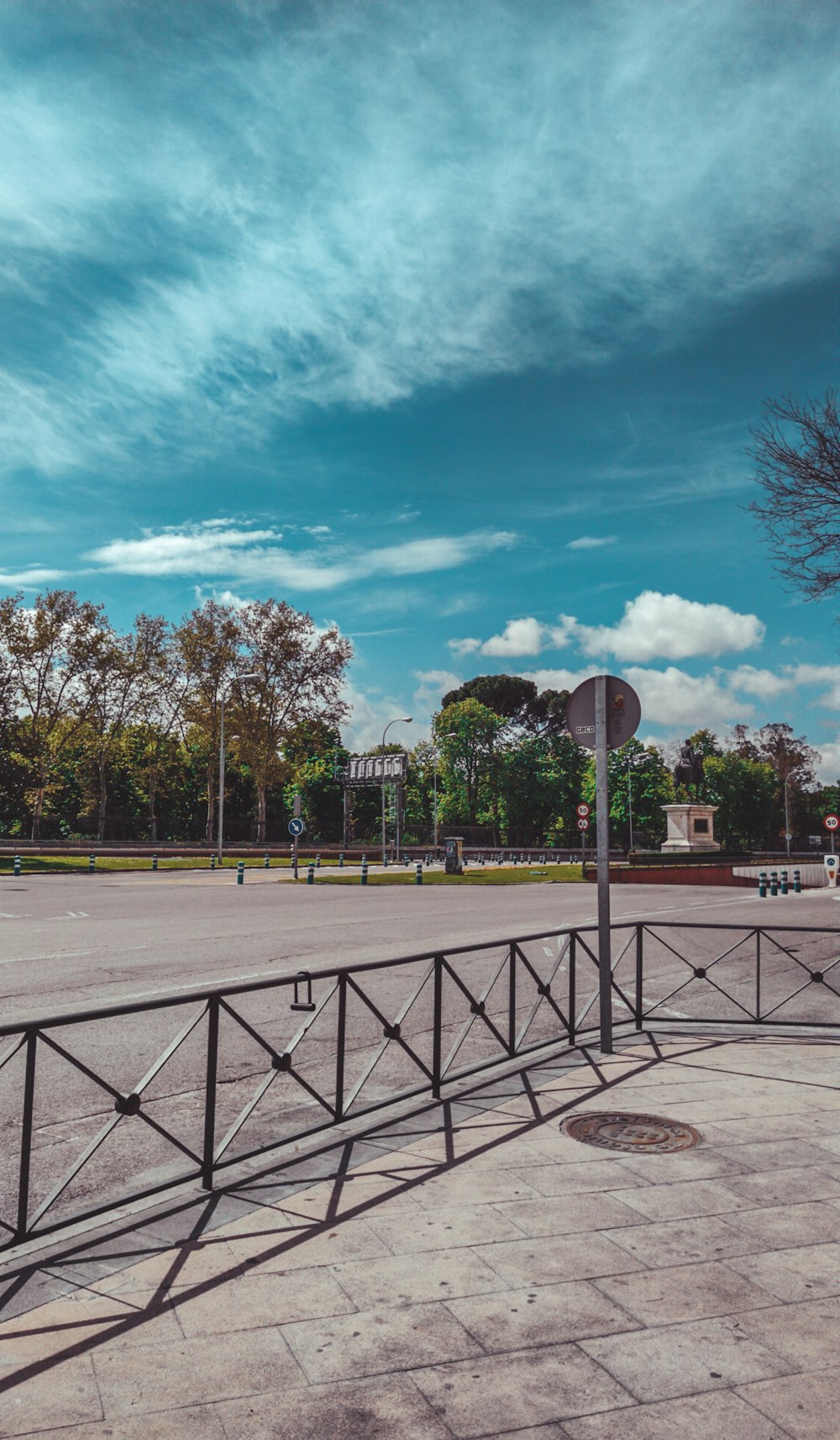 cancha de baloncesto rodeada de árboles bajo el cielo azul y nubes blancas durante el día